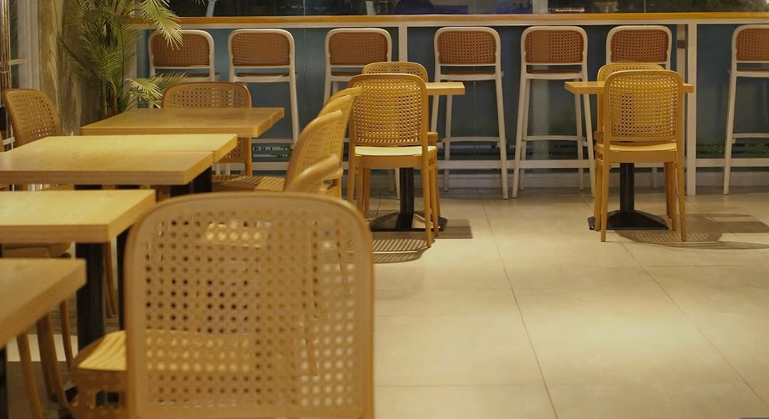 Happy Valley Café interior — rattan chairs and white tile floors at dusk